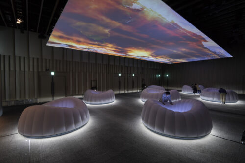 Exhibition showing inflatable wells displaying video content underneath images of disasters projected on the ceiling